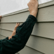 Contractor installing vinyl siding.